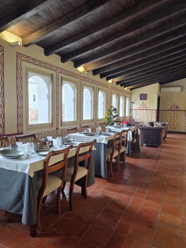ein Esszimmer mit Tischen, Stühlen und Fenstern in der Unterkunft La PuertaMora in Orgaz