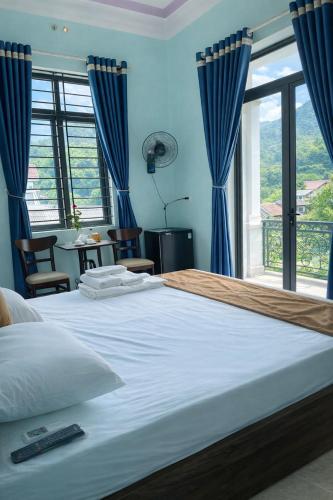 a bedroom with a large bed with blue curtains at Chely Hotel in Mù Cang Chải