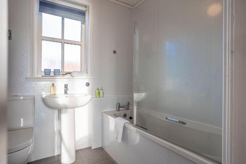 a white bathroom with a sink and a bath tub at Shore Cottage - Lower Largo in Lower Largo