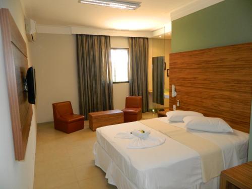 a hotel room with a white bed and a chair at Hotel Recreio São Jorge in Jabuticabal