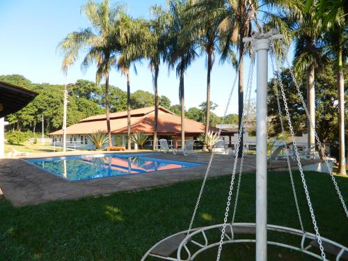a pool with palm trees next to a resort at Hotel Recreio São Jorge in Jaboticabal