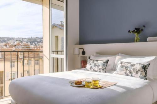 a white bed with two drinks and a tray of food on it at Crisol Mozart in Nice