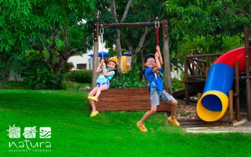 two children playing on a swing in a park at Natura Reservado - Hoteles Natura in Anapoima