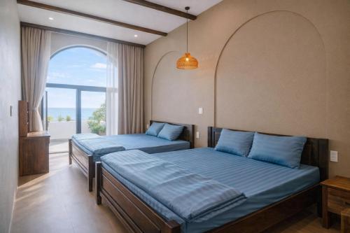 two beds in a room with a window at HiDra Homestay in An Tịnh