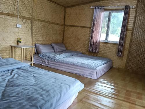 een slaapkamer met twee bedden en een raam erin bij จรรยา โฮมเสตย์ in Chom Thong