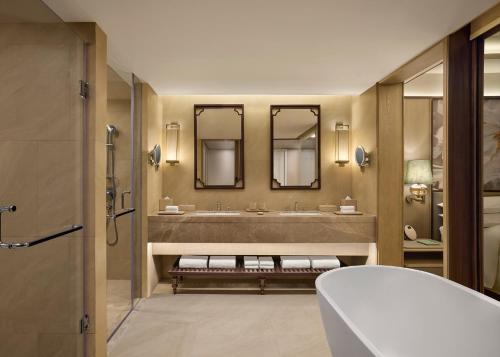 een badkamer met een grote wastafel en 2 spiegels bij Renaissance Goa Hotel in Goa