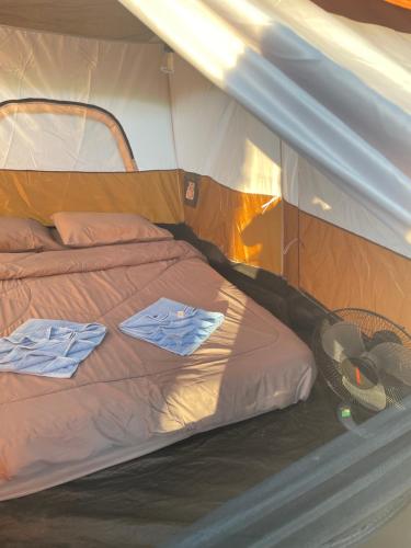 een bed in een tent met twee overhemden erop bij Kohkood camp in Ban Khlong Mat