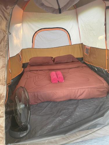 een bed in een tent met twee roze slippers bij Kohkood camp in Ban Khlong Mat