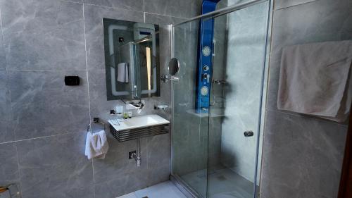 a bathroom with a shower with a sink and a mirror at Hôtel Nyota Lodge Kolwezi in Kolwezi