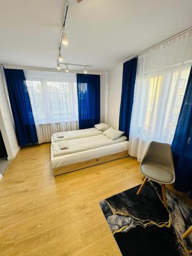 een slaapkamer met blauwe gordijnen en een bed en een stoel bij Kwatera na Zakładowej in Starachowice