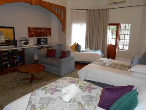 a hotel room with two beds and a chair at Dreamers Guesthouse - NO LOADSHEDDING in King Williamʼs Town