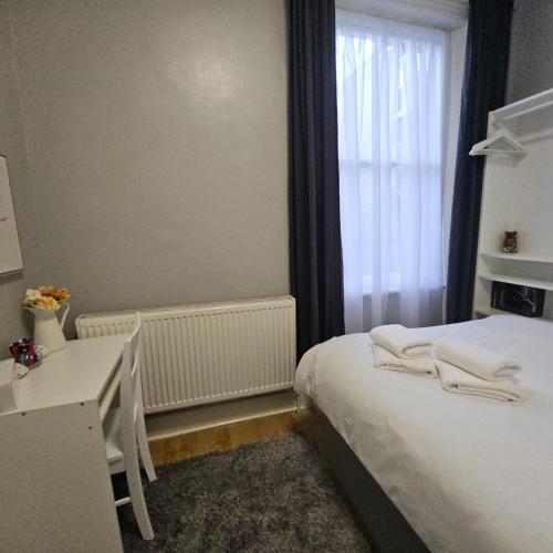 a bedroom with a bed and a desk and a window at Comfortable Private Rooms in Central London Next to Station in London