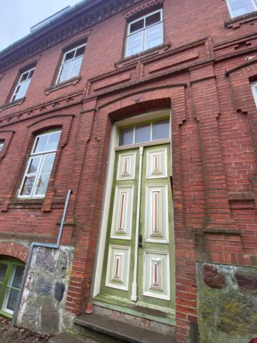 ein rotes Backsteingebäude mit grüner Tür in der Unterkunft SecondHomeViljandi Apartment in Viljandi