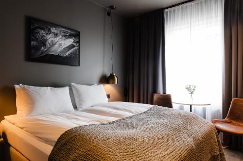 Schlafzimmer mit einem Bett, einem Fenster und einem Tisch in der Unterkunft Hotel Ódinsvé in Reykjavík