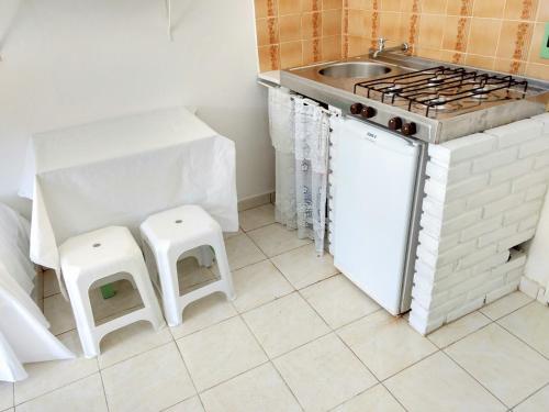 a kitchen with a sink and a stove and stools at Apartamentos Atobá Flats in Juquei