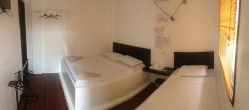 Cette petite chambre comprend 2 lits et une fenêtre. dans l'établissement Lola's Lodge, à Boracay