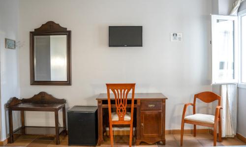 um quarto com uma secretária, 2 cadeiras e um espelho em La Palmosa em Alcalá de los Gazules