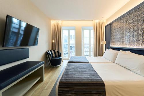 a hotel room with a bed and a flat screen tv at Catalonia Porto in Porto