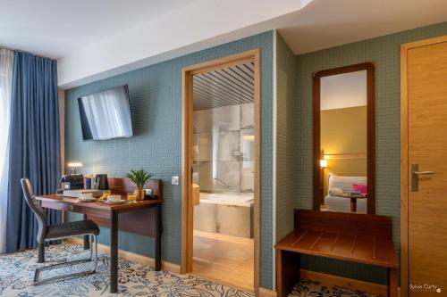 een hotelkamer met een bureau en een badkamer bij Hôtel Le Yachtman, The Originals Collection in La Rochelle