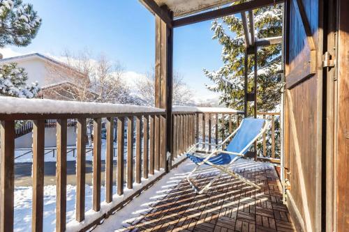 a rocking chair on a porch in the snow at Hostdomus - La Chapelle in Sauze d'Oulx