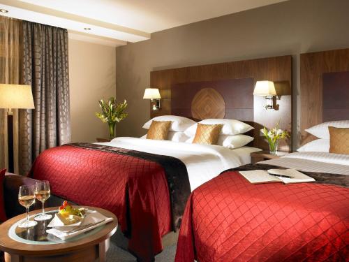 a hotel room with two beds and a table with wine glasses at Westport Plaza Hotel, Spa & Leisure in Westport