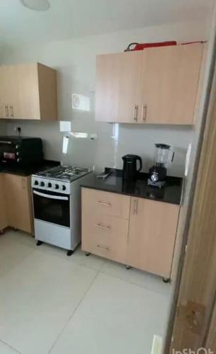 een kleine keuken met een fornuis en kasten bij Modern Apartment in Muscat in Muscat