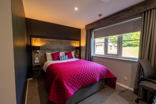 ein Schlafzimmer mit einem rosa Bett und einem Fenster in der Unterkunft The Willows Training Centre in Saint Neots