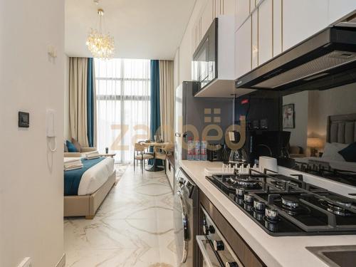 a kitchen with a stove top oven next to a living room at Zapbed House-Modern Studio-Petalz By Danube in Dubai