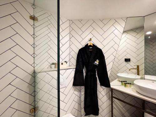 a black jacket hanging on a wall in a bathroom at מלון ארנה בת ים - קומת סוויטות הגן עם סאונה פרטית in Bat Yam