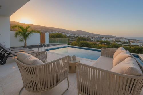 a patio with a table and chairs and a swimming pool at Sunny Ocean View Villa - Calma in Estreito da Calheta