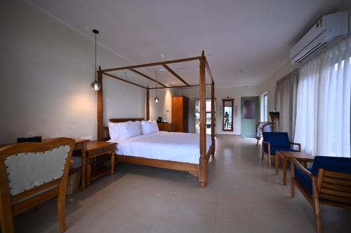 a bedroom with a bed and a table and chairs at Vedic Village Retreat Alleppey in Alleppey