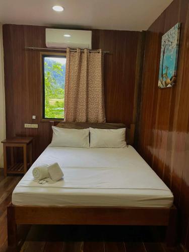 a bed in a small room with a window at Kenji Guest House in San Vicente