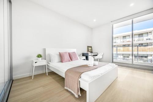 a white bedroom with a bed and a large window at Tranquil Studio in Schofields in Schofields