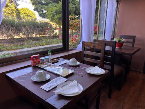 een houten tafel met borden en schalen erop naast een raam bij Hostal Boutique 180 Grados in Algarrobo