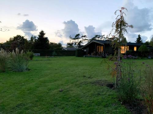 un ampio cortile con una casa sullo sfondo di Summer Bliss With Vibrant Garden In Nødebohuse a Kikhavn