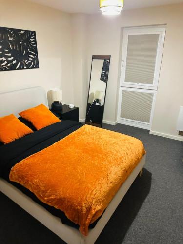 a bedroom with a bed with an orange blanket at Executive 2 Bed Condo with Free Parking in Manchester