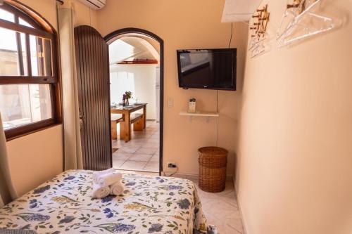 a bedroom with a bed and a tv on the wall at Recanto aconchego in Peruíbe