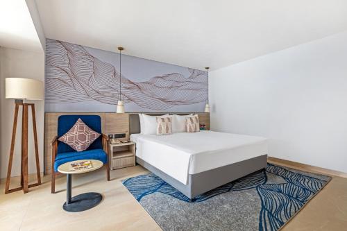 een slaapkamer met een wit bed en een blauwe stoel bij Sterling Arka Suites, Puri in Puri
