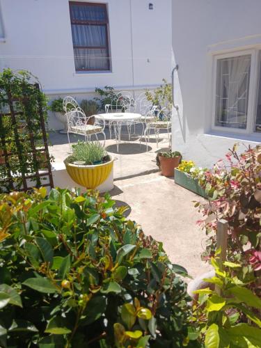 een terras met een tafel, stoelen en planten bij Jann's Cozy Cottage in Bredasdorp