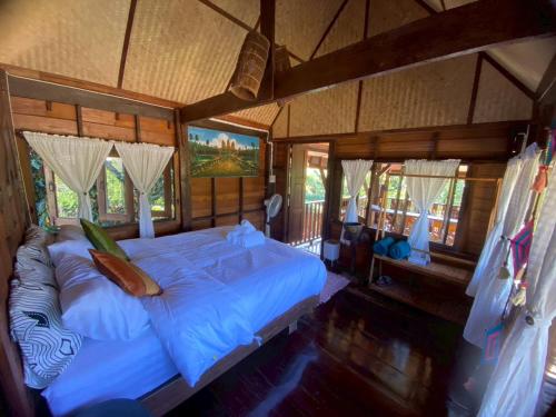 een slaapkamer met een groot bed in een kamer met ramen bij Elephant House and Pool Villas 