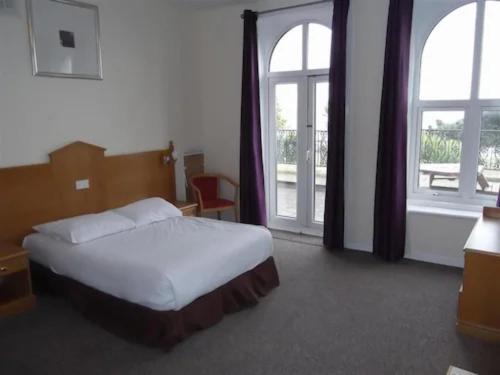 een slaapkamer met een bed en 2 grote ramen bij Esplanade Hotel - Clacton On Sea, Beachfront Hotel by OYO in Clacton-on-Sea