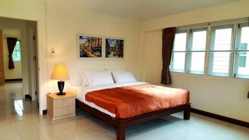 una camera da letto con un letto con una lampada e finestre di Family Resort Khao Yai a Pak Chong