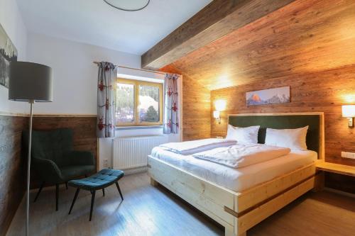 een slaapkamer met een bed, een stoel en een raam bij Appartements Alpenland in Lermoos