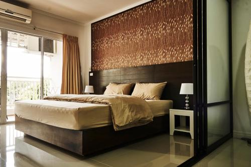 a bedroom with a large bed with a large headboard at Baan Klang Condo Hua Hin in Hua Hin