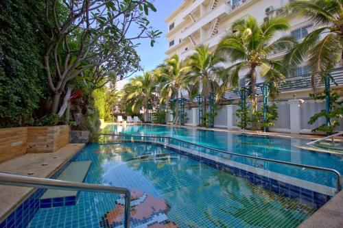 a swimming pool in front of a building with palm trees at Baan Klang Condo Hua Hin in Hua Hin