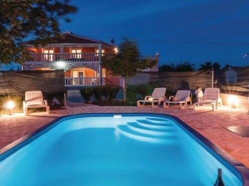 a swimming pool with chairs and a house in the background at Apartment Laura mit Pool by Interhome in Stankovci