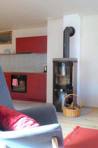 a living room with a fireplace with a chair and a kitchen at Apartment Biala - BioBergün by Interhome in Bergün