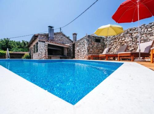 a villa with a swimming pool and a red umbrella at Holiday Home Villa Rokov in Mali Iž