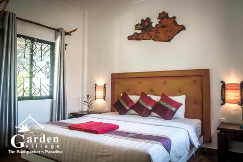 a bedroom with a large bed with red pillows at Garden Village Guesthouse & Pool Bar in Siem Reap