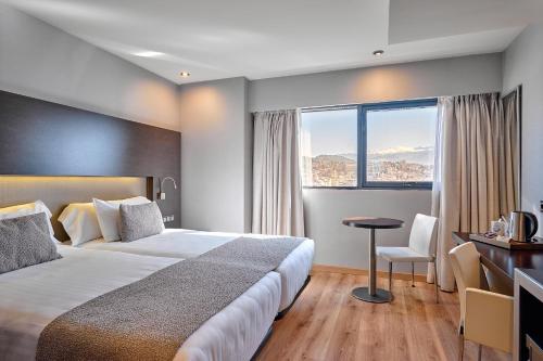 a hotel room with a bed and a desk and a window at Turia Granada in Granada